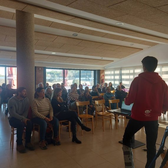 Una persona jove d'esquenes a un auditori fa la presentació d'un treball de recerca