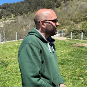Imatge de tres quarts del perfil d'un home, vestit amb una dessuadora verda, en un prat